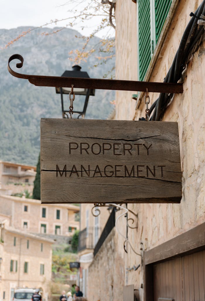 Wooden property management sign in a picturesque European village, featuring charming architecture.