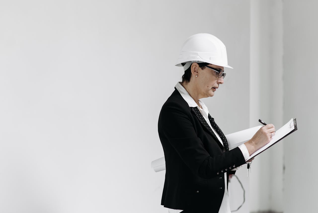 services-02 Woman in business attire with hard hat taking notes at a construction site.